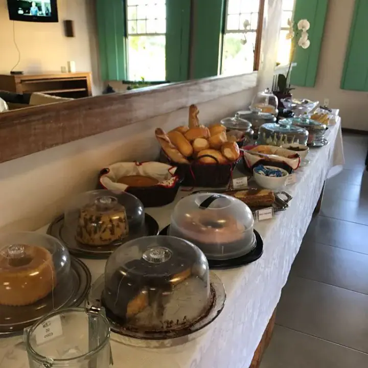 Mesa completa do café da manhã, com pães, bolos, cestas, louças e recipientes