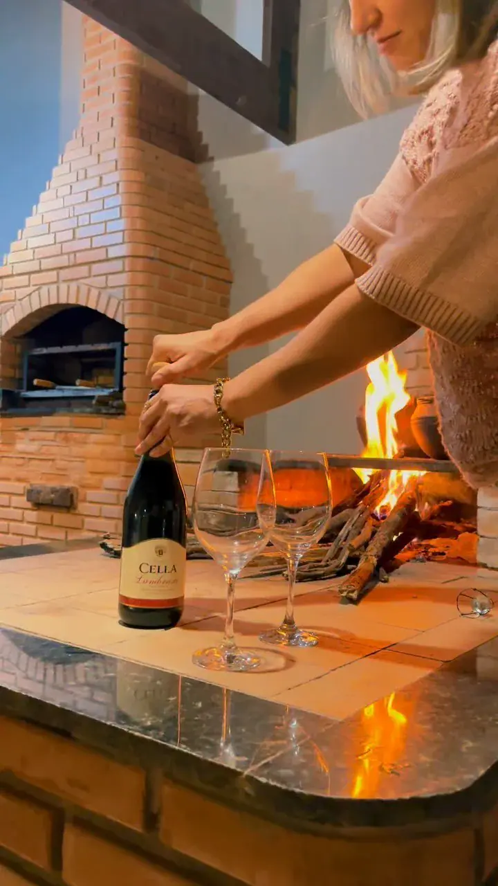 Fogo aceso junto à parede de tijolos e uma taça de vinho